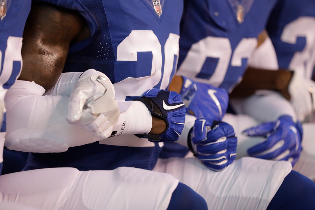 Members of the Indianapolis Colts lock arms as they take a knee during the Nation Anthem before an NFL football game against the Cleveland Browns in Indianapolis, Sunday, Sept. 24, 2017. (AP Photo/Darron Cummings)