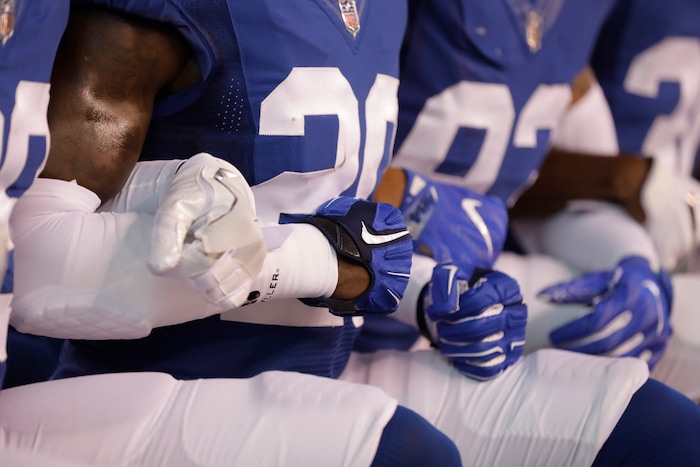 Members of the Indianapolis Colts lock arms as they take a knee during the Nation Anthem before an NFL football game against the Cleveland Browns in Indianapolis, Sunday, Sept. 24, 2017. (AP Photo/Darron Cummings)