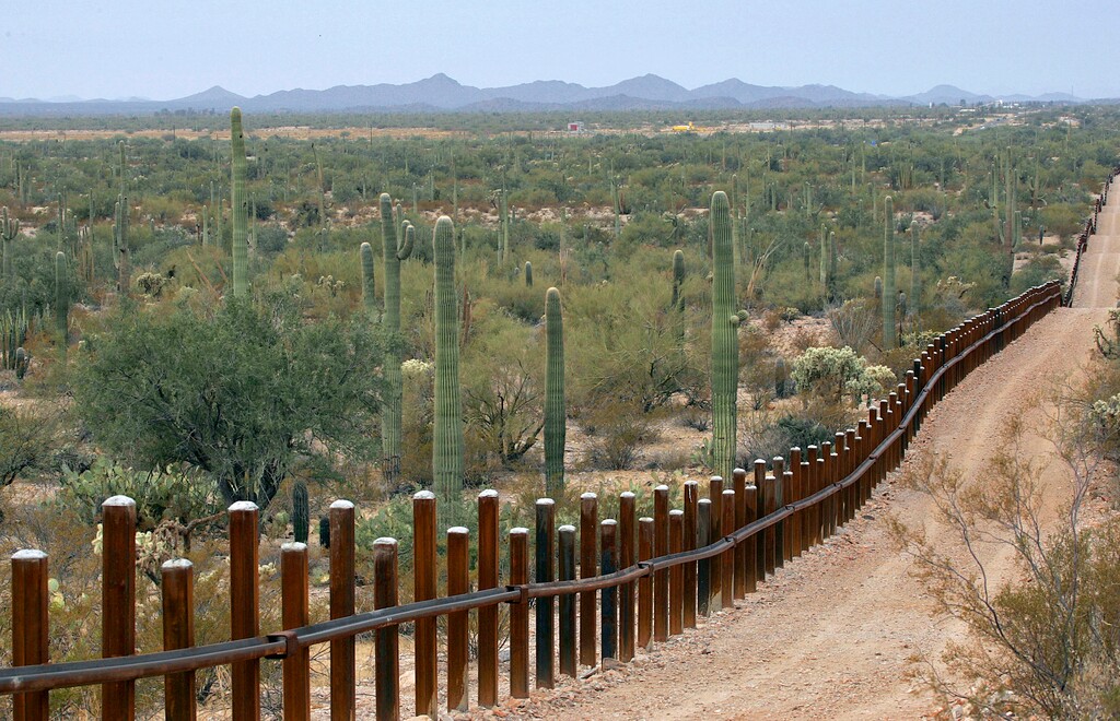 FILE - This Feb. 17, 2006 file photo shows the international border line made up of bollards: irregular, concrete-filled steel poles, seperating Mexico, left from the United States, in the Organ Pipe National Monument near Lukeville, Ariz. The federal government plans on replacing barriers through 100 miles of the southern border in California and Arizona, including through a this national monument and a wildlife refuge, according to government documents and environmental advocates. The Department of Homeland Security on Tuesday waived environmental and dozens of other laws to build more barriers along the southern border. (AP Photo/Matt York, File)