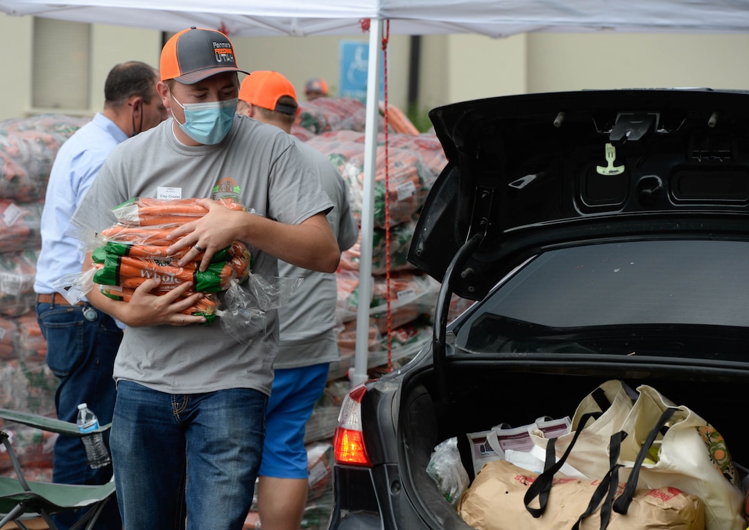 (Francisco Kjolseth  |  The Salt Lake Tribune) Clay Crozier offers up carrots for the third “Miracle Project” for the nonprofit foundation which raises money to purchase food produced by Utah farmers and then gives to residents in need, takes place at the Utah State Fairpark in Salt Lake City on Monday, July 27, 2020. The food donation from the Utah Farm Bureau’s “Farmers Feeding Utah” program provided food for 600 individuals and families who have recently become unemployed due to the coronavirus.