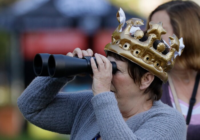 A woman with an inflatable crown looks through binoculars prior to the wedding ceremony of Prince Harry and Meghan Markle at St. George's Chapel in Windsor Castle in Windsor, near London, England, Saturday, May 19, 2018. (AP Photo/Kirsty Wigglesworth)
