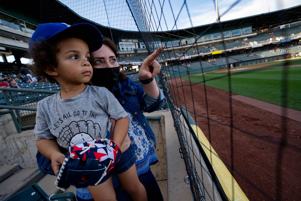 (Francisco Kjolseth | The Salt Lake Tribune) “Auntie” Jess Anderson points out baseball players warming up on the field to Ethan Goss, 2, as they attend the Salt Lake Bees home open at Smith’s Ballpark Thursday night, May 6, 2021. Baseball fans can exchange their Smith's receipts of $75 or more for free Bees tickets.