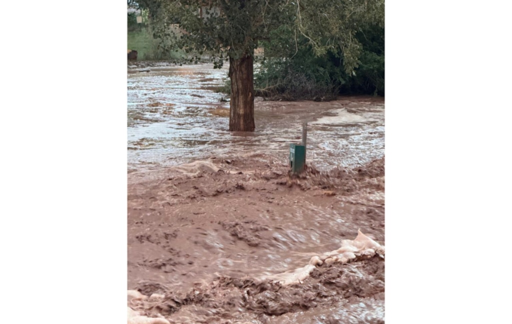 (Britta Kingsley | The Times-Independent) A dog-waste bag dispenser is nearly submerged in floodwaters in Moab on Aug. 23, 2024.