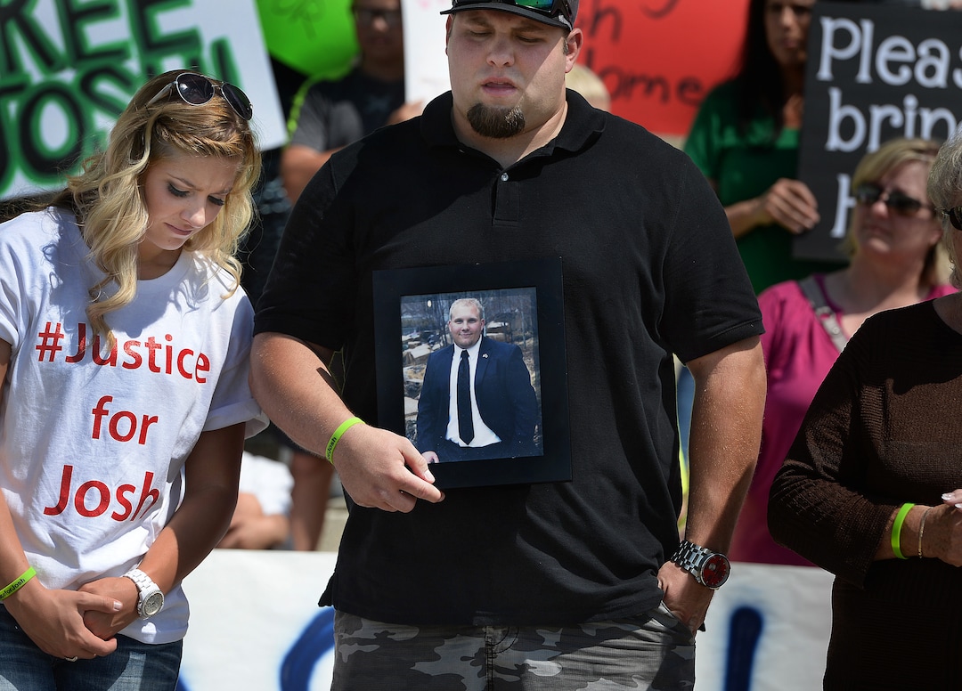 Scott Sommerdorf   |  The Salt Lake Tribune  Josh Holt's brother Derek Holt holds a photo of Josh with sister Jenna at left during a rally on the east steps of the Utah State Capitol for 24-year-old Josh Holt, who is currently jailed in Venezuela, Saturday, July 30, 2016. 