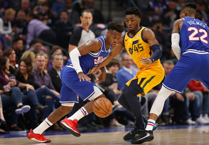 Sacramento Kings guard Buddy Hield, left, uses a screens by  Richaun Holmes, right, as he tries to leave Utah Jazz guard Donovan Mitchell behind during the first quarter of an NBA basketball game in Sacramento, Calif., Friday, Nov. 1, 2019. (AP Photo/Rich Pedroncelli)