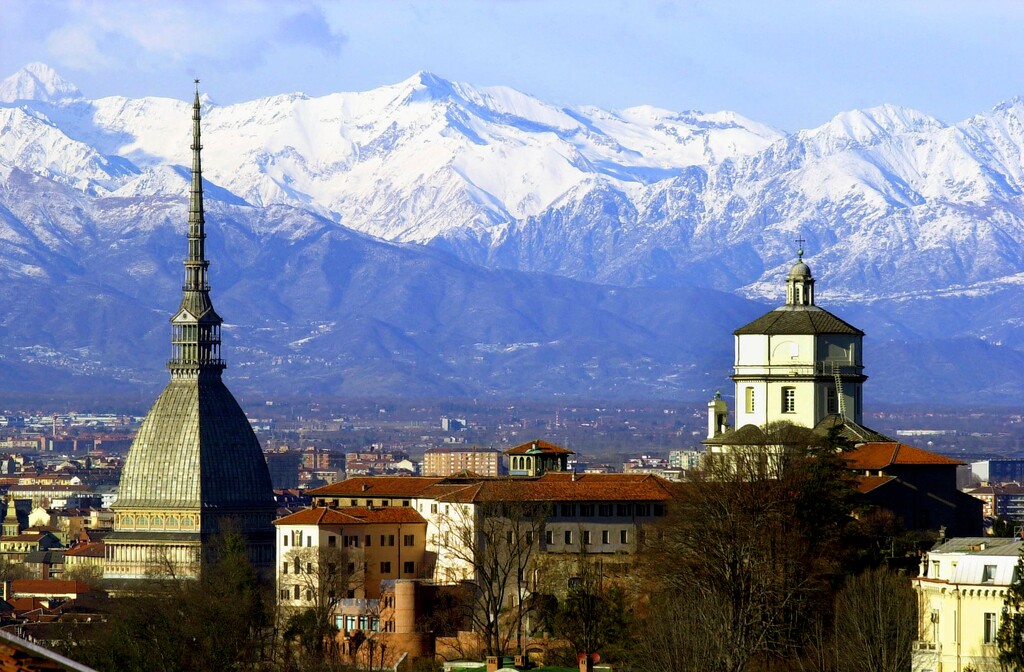 FILE - In this Feb. 20, 2006 file photo, the Mole Antoneliana, left, Turin's most famous landmark, is backdropped by the Alps, in Turin, northern Italy. Italy will launch a three-city bid to host the 2026 Winter Olympics in Milan, Turin and Cortina. The Italian Olympic Committee announced the move on Wednesday Aug. 1, 2018, having decided a joint bid was more cost effective. (AP Photo/Massimo Pinca, file)