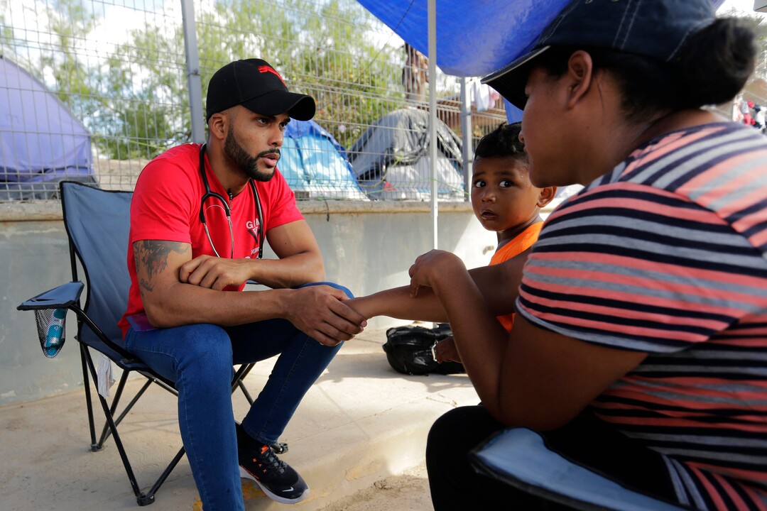 In this Wednesday, Nov. 6, 2019, Dairon, a doctor from Cuba who is seeking asylum in the U.S. attends to fellow migrants at a sidewalk clinic in a refugee camp in Matamoros, Mexico. The few doctors and nurses working in the camp are treating people including pregnant women and children with respiratory problems, skin conditions, diarrhea, and other diseases that can be linked to the camp’s unsanitary conditions. (AP Photo/Eric Gay)