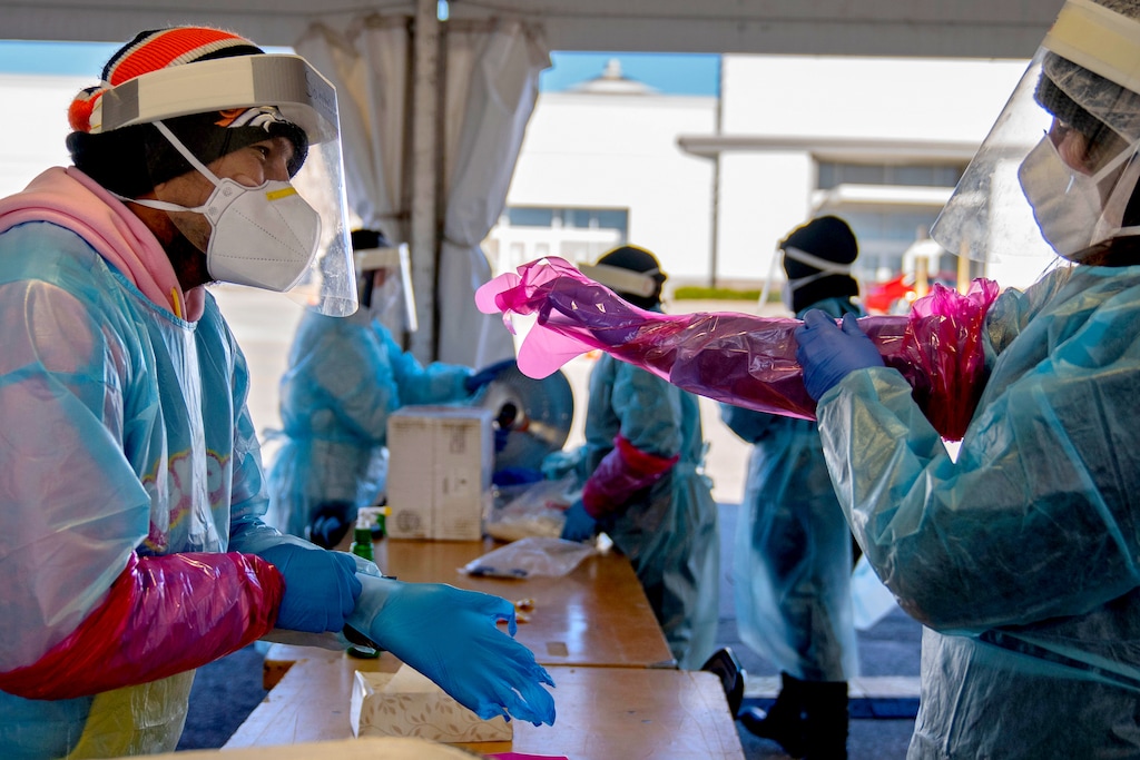 (Calla Kessler | The New York Times) Medical workers don personal protective equipment before testing people for the coronavirus at a mall in Omaha, Neb., Nov. 13, 2020. The seven-day average of new daily cases is more than 140,000, with upward trends in 49 states. Some 30 states added more cases in the last week than in any other seven-day period.