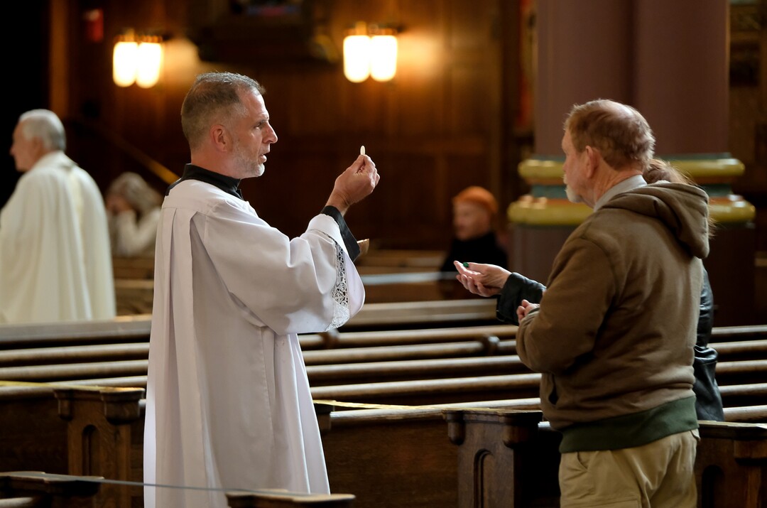 (Francisco Kjolseth  |  The Salt Lake Tribune) Catholic parishioners remain by their pews as altar assistant Darren Williams delivers Communion during morning Mass at Cathedral of the Madeleine in Salt Lake City on Friday, May 8, 2020. Numerous restriction have been implemented in order to battle the coronavirus pandemic as worship services begin to reopen.