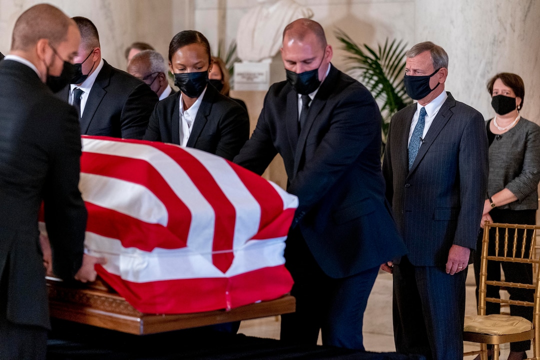 Chief Justice of the United States John Roberts, second from right, and Justice Elena Kagan, right, watch as the flag-draped casket of Justice Ruth Bader Ginsburg arrives at the Supreme Court in Washington, Wednesday, Sept. 23, 2020. Ginsburg, 87, died of cancer on Sept. 18. At far right is Associate Justice Elena Kagan. (AP Photo/Andrew Harnik, Pool)