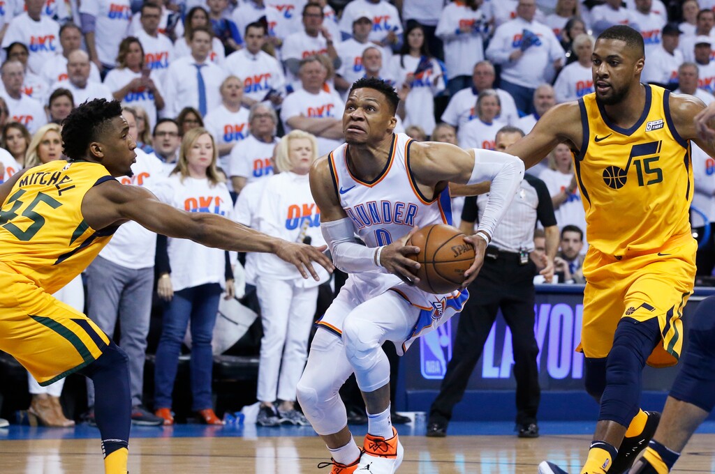 Oklahoma City Thunder guard Russell Westbrook (0) drives between Utah Jazz guard Donovan Mitchell (45) and forward Derrick Favors (15) during the first half of Game 2 of an NBA basketball first-round playoff series in Oklahoma City, Wednesday, April 18, 2018. (AP Photo/Sue Ogrocki)