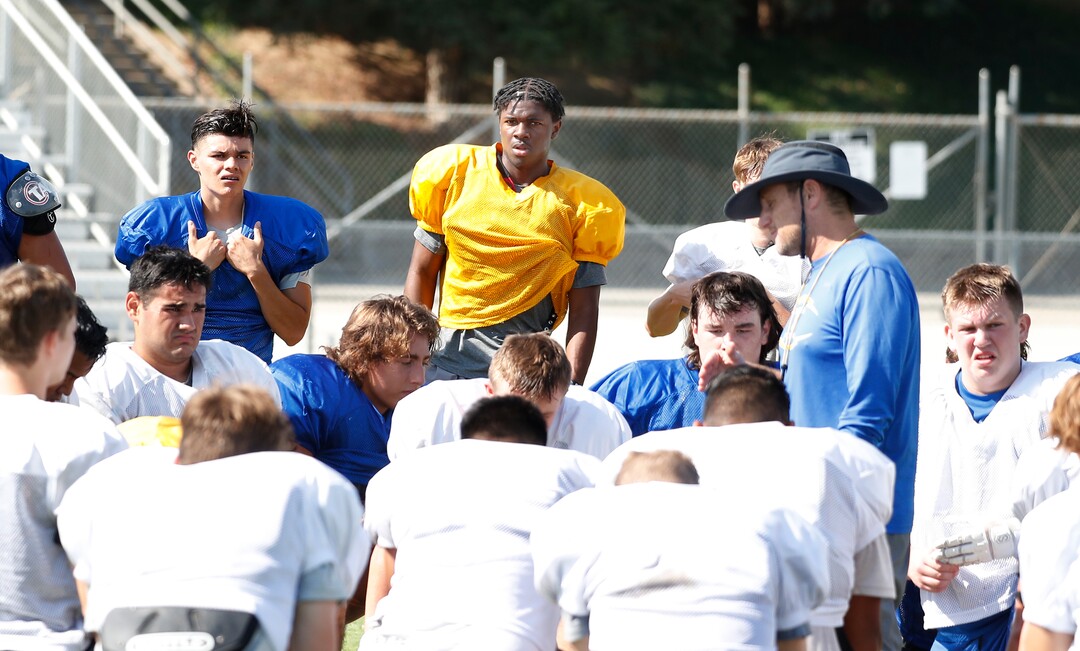 (Gary Kazanjian | Special to The Tribune) Clovis High School quarterback Nate Johnson, shown in the background, as his team as head coach Rich Hammond talks to the team at Clovis High School, who committed to play for the University of Utah, shown Wednesday, July 28, 2021, in Clovis, Calif.