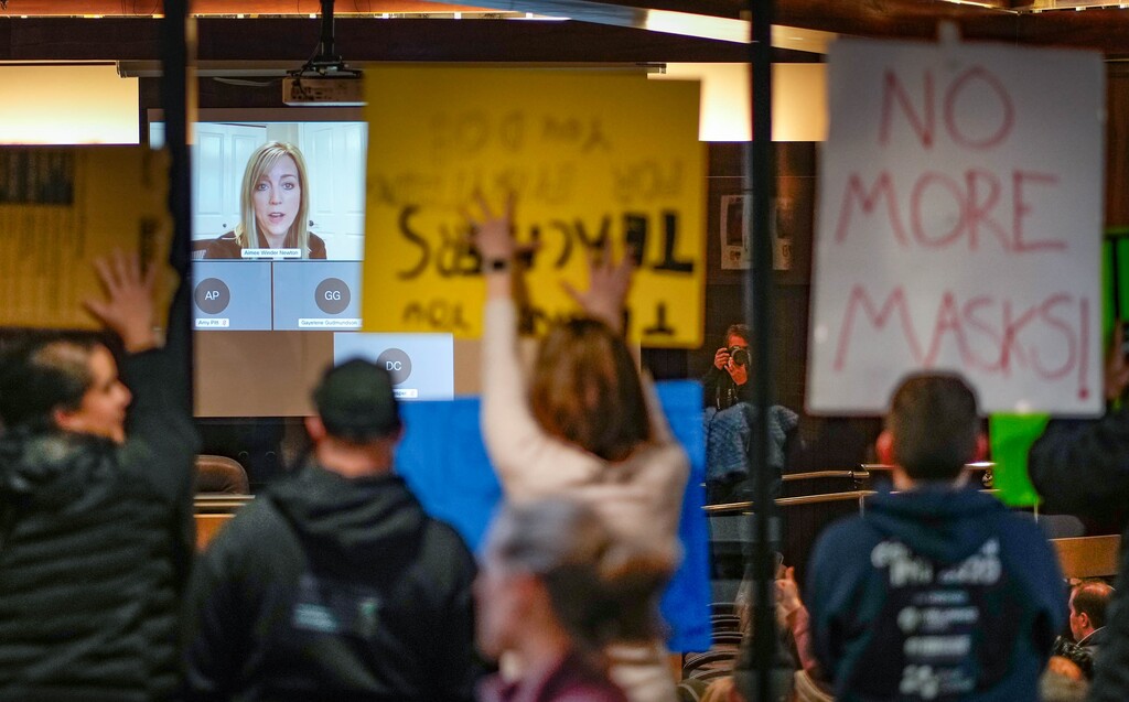 (Francisco Kjolseth | The Salt Lake Tribune) People gather at the Salt Lake County Government Center on Thursday, Jan. 13, 2022, to protest and support the recent mask mandate issued by the Salt Lake County Health Department and Mayor Jenny Wilson. Council member Amy Winder Newton speaks remotely as people resort to holding up signs against the glass to the chamber as the council takes another vote which kept the mandate in place. 