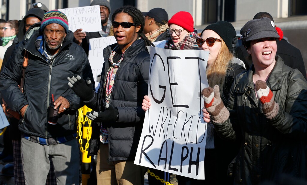 Demonstrators hold signs and chant outside the Governors office at the Capitol in Richmond, Va., Saturday, Feb. 2, 2019. The demonstrators are calling for the resignation of Virginia Governor Ralph Northam after a 30 year old photo of him on his medical school yearbook photo was widely distributed Friday. (AP Photo/Steve Helber)