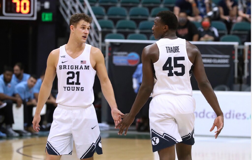 BYU guard Trevin Knell (21) and forward Fousseyni Traore (45) slap hands during the second half of the team's NCAA college basketball game against Liberty on Saturday, Dec. 25, 2021, in Honolulu. (AP Photo/Marco Garcia)