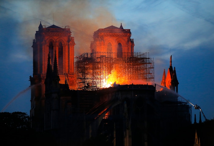 Firefighters tackle the blaze as flames and smoke rise from Notre Dame cathedral as it burns in Paris, Monday, April 15, 2019. Massive plumes of yellow brown smoke is filling the air above Notre Dame Cathedral and ash is falling on tourists and others around the island that marks the center of Paris. (AP Photo/Michel Euler)