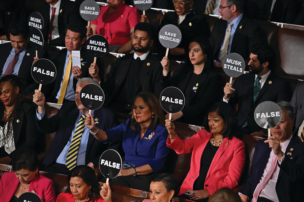 Attendees hold up signs as they protest during President Donald Trump’s address to a joint session of Congress at the Capitol in Washington, on Tuesday, March 4, 2025. (Kenny Holston/The New York Times)
