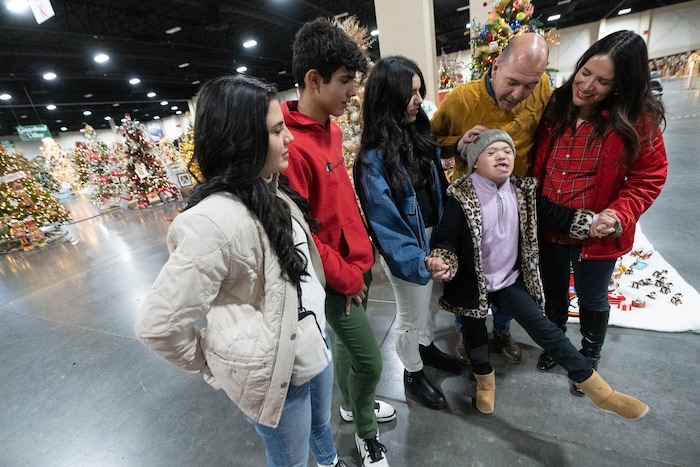 (Francisco Kjolseth | The Salt Lake Tribune) Sophia Mousques, 14, gestures to “kick cancer in the butt,” as she is joined by her family Giovanna, Andrew, Alessa, from left, and her parents Nelson and Claudia while at the Fetstival of Trees at the Mountain America Expo Center in Sandy on Tuesday, Nov. 30, 2021. Sophia who’s home away from home has been Primary Children’s Hospital since she was born with down syndrome, only two chambers in her heart and leukemia, has been an inspiration to her family as they bring attention to all the support the hospital has provided.