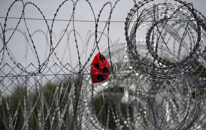 A punctured ball hangs on barbed wire in the heavily guarded camp at Serbia's border with Hungary, near the Horgos border crossing, Serbia, Tuesday, Sept. 19, 2017. The European Union border that saw hundreds of thousands of migrants enter freely in 2015 has since become a sealed fortress with two rows of fence and closed border camps that the United Nations have described as “in effect detention centers.” (AP Photo/Darko Vojinovic)