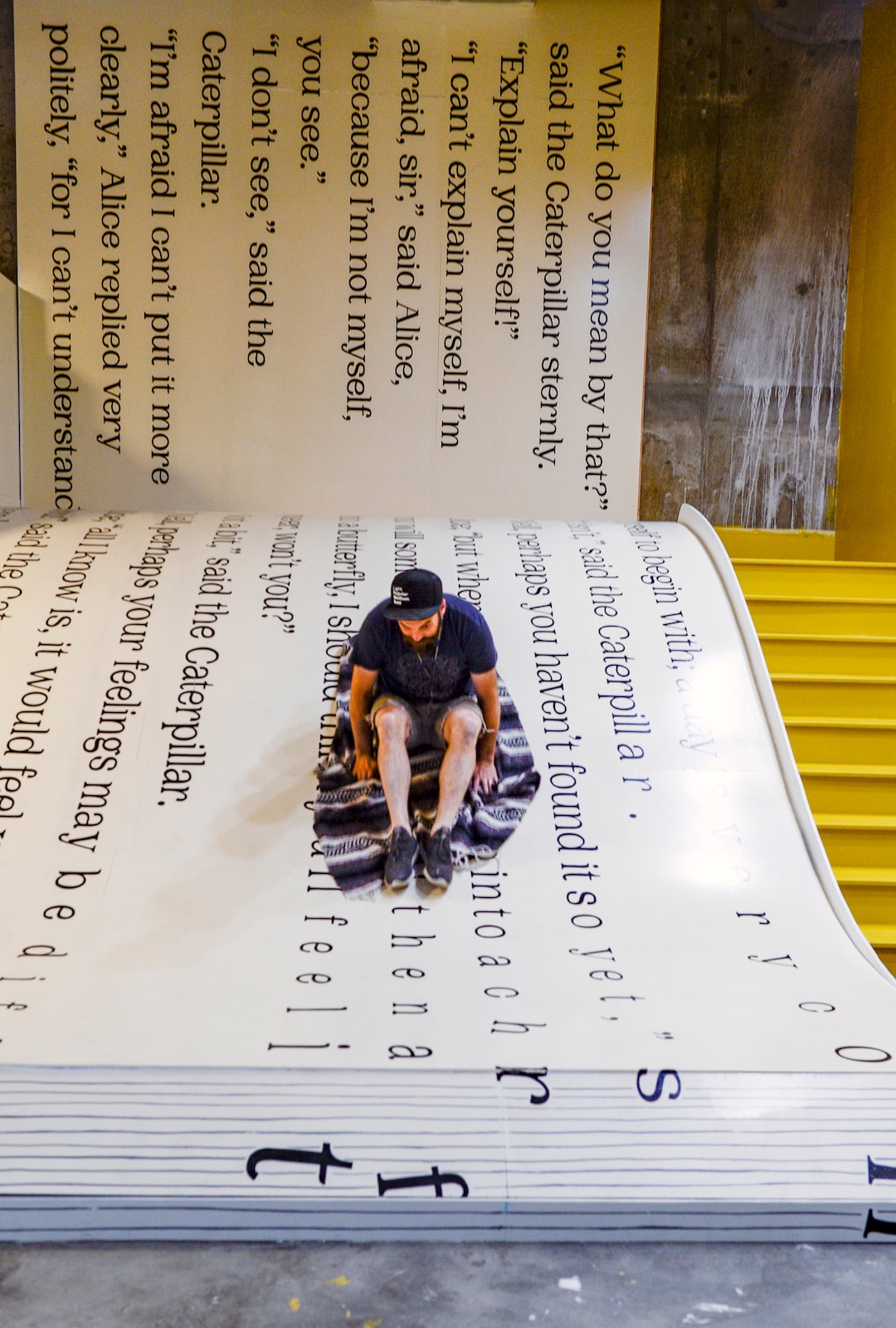 (Leah Hogsten  |  The Salt Lake Tribune) Love Letters Museum co-designer and artist John Connors slides down a giant book replica of “Alice in Wonderland” as part of the Love Letters Museum show opening June 21, 2109. Love Letters is the newest 15,000-square-foot interactive art installation at The Gateway dedicated to the love of letters, as well as typography, books and literal love letters. “It is our attempt to use what we know best (letters, words, and art) to encourage each of our visitors to find and tell their own story. And to find the art in other's stories” -Love Letters Museum. ​