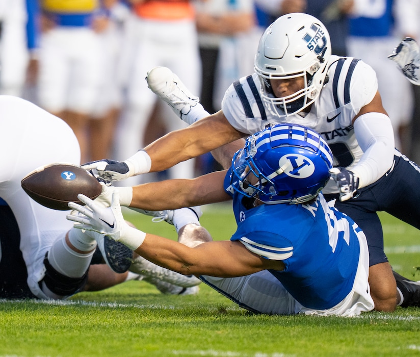 (Rick Egan | The Salt Lake Tribune) Brigham Young Cougars running back Lopini Katoa (4) tries to hold on to the ball, as Utah State Aggies linebacker AJ Vongphachanh (10) goes after the loose ball, in Football action between the Brigham Young Cougars and the Utah State Aggies, at LaVell Edwards Stadium in Provo, on Thursday, Sept. 29, 2022.