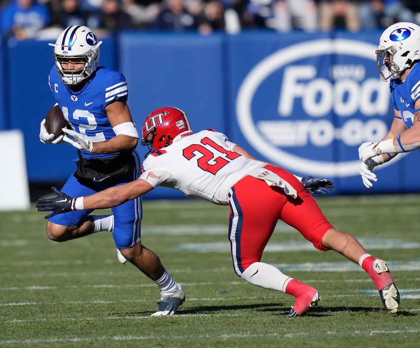 a(Francisco Kjolseth | The Salt Lake Tribune) Brigham Young Cougars wide receiver Puka Nacua (12) is pressured by Utah Tech's Will Leota (21) in football action between the Brigham Young Cougars and the Utah Tech Trailblazers at LaVell Edwards Stadium in Provo, Saturday, Nov. 19, 2022.