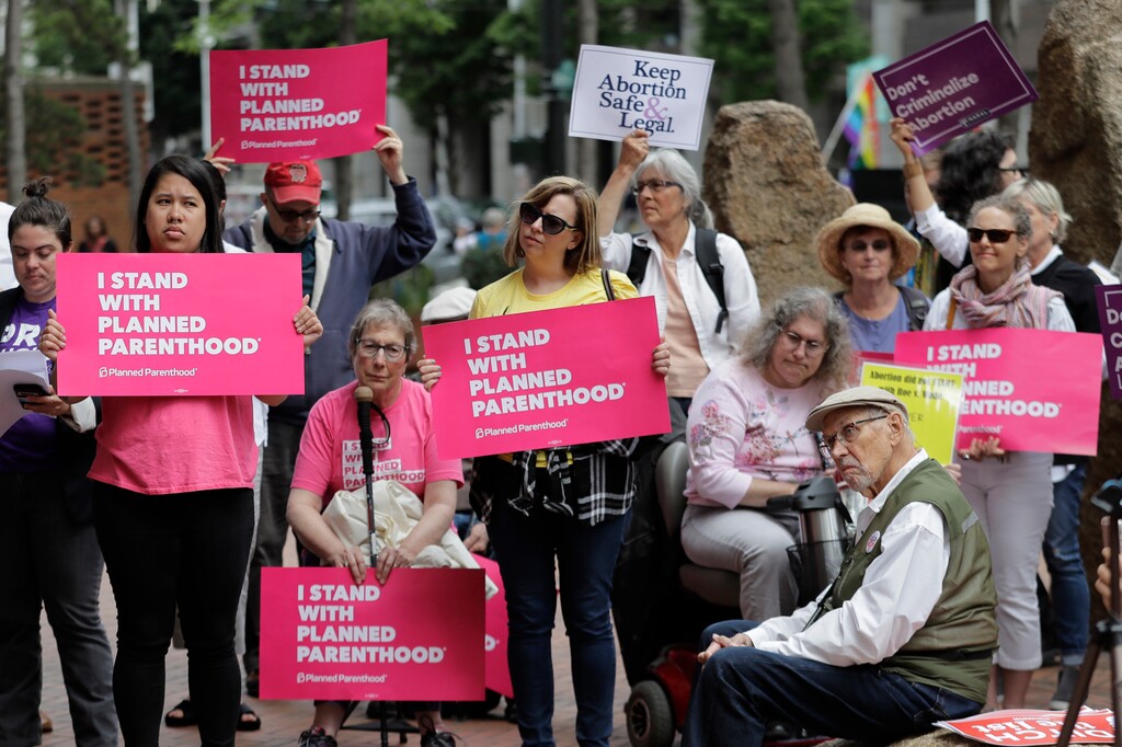 (AP Photo/Ted S. Warren, File) In this July 10, 2018 file photo, protesters hold signs supporting Planned Parenthood in Seattle, as they demonstrate against President Donald Trump and his choice of federal appeals Judge Brett Kavanaugh as his second nominee to the Supreme Court. On Tuesday, March 5, 2019, the American Medical Association and Planned Parenthood jointly filed a federal court lawsuit challenging a new Trump administration rule for family-planning grants which had been sought by anti-abortion activists.