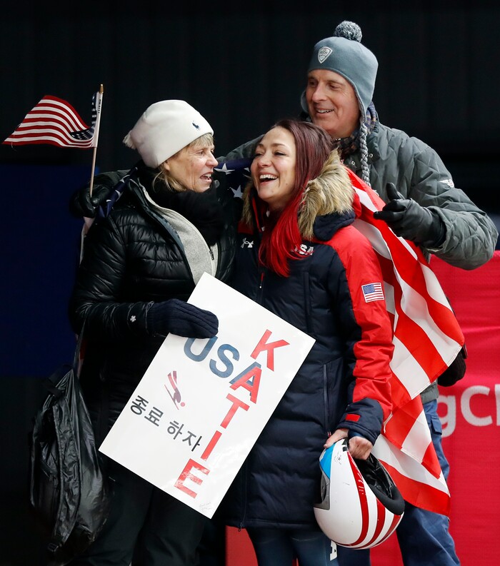 Katie Uhlaender of United States, center, is hugged and kissed by Jean Schaefer, left, and Dr. Brian Boxer Wachler in the finish area after the final run of the women's skeleton competition at the 2018 Winter Olympics in Pyeongchang, South Korea, Saturday, Feb. 17, 2018. Schaefer is the mother of deceased American bobsledder Steve Holcomb and Wachler is a Holcomb family friend and doctor. They came to support Uhlaender, who was friends with Holcomb. (AP Photo/Andy Wong)