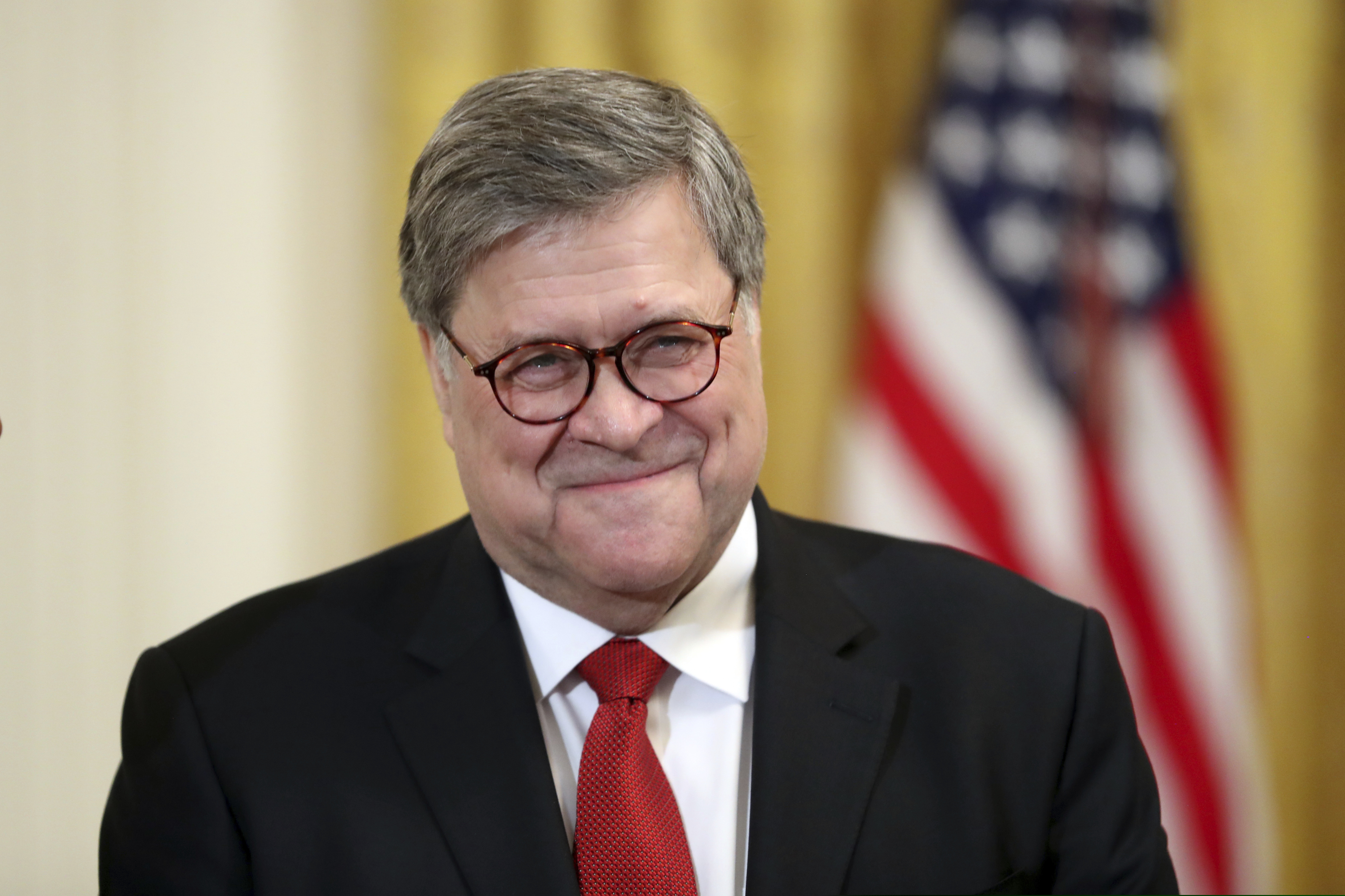 (Andrew Harnik  |  AP Photo)  Attorney General William Barr smiles as he waits for President Donald Trump to speak at the 2019 Prison Reform Summit and First Step Act Celebration in the East Room of the White House in Washington, Monday, April 1, 2019.