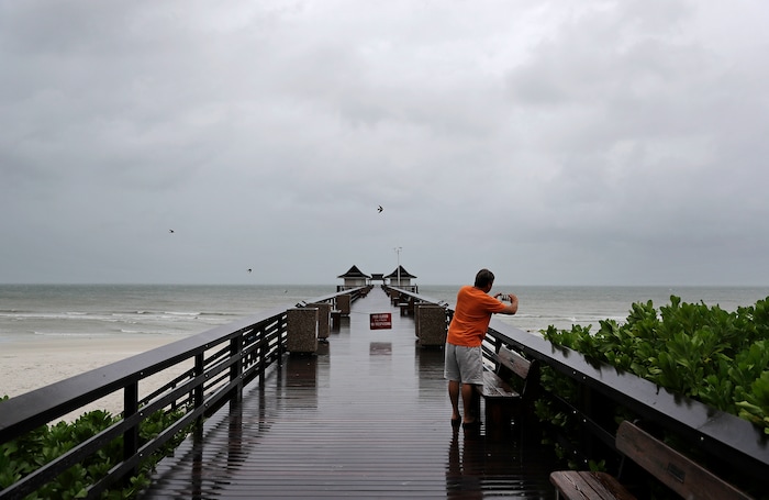 (AP Photo/David Goldman) Keith Gahagan takes a photo of the early effects of Hurricane Irma in Naples, Fla., Sunday, Sept. 10, 2017. Gahagan plans on riding out the storm in Naples but on higher ground further inland.