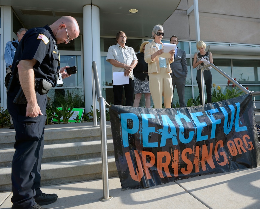 Al Hartmann |  The Salt Lake TribuneA small group from Peaceful Uprising, Utah Tar Sand Resistence and concernced citizens read statements and performed a skit with children on the steps of the Utah Dept. of Natural Rescources as a security man records them before a crucial hearing Tuesday June 30 at the Utah Board of Oil, Gas and Mining in Salt Lake City.  