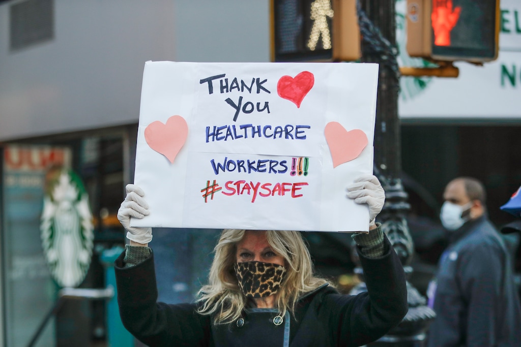 A person holds up a sign as police officers and pedestrians cheer for nurses and medical workers at Lenox Hill Hospital Wednesday, April 15, 2020, in New York. (AP Photo/Frank Franklin II)