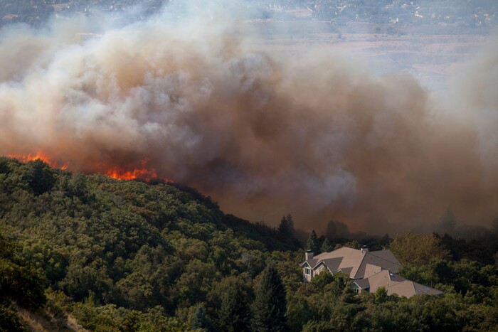 In this Tuesday, Sept. 5, 2017, photo, a wildfire burns through residential areas near the mouth of Weber Canyon near Ogden, Utah. (Benjamin Zack/Standard-Examiner via AP)