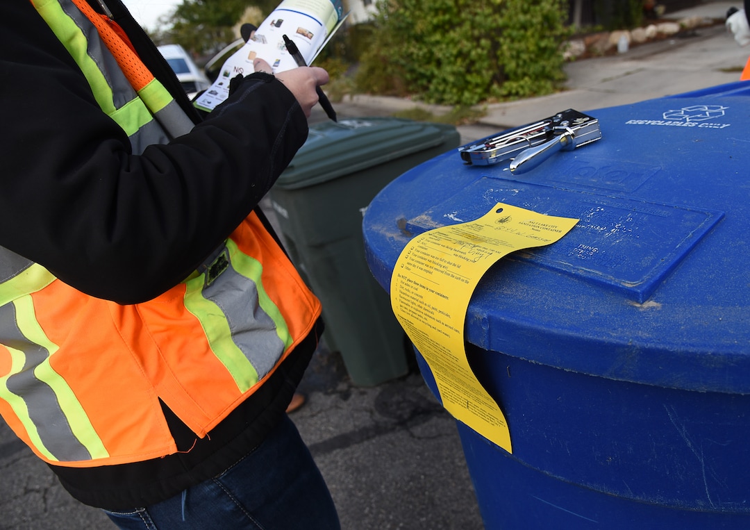 (Francisco Kjolseth  |  The Salt Lake Tribune)  Jen Farrell, lead outreach and education specialist for Salt Lake City Corporation Sanitation Division places a notice on a recycle bin for the recycle truck not to collect that week after finding a large tent like canvas with rope buried deep inside the bin. Salt Lake City employees go around the city and look into people's recycling bins in an effort to educate the public on what can and can't be recycled to reduce problems in the recycling stream