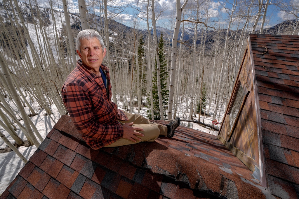 (Francisco Kjolseth | The Salt Lake Tribune) Ross McIntyre, who has lived across from Solitude Mountain Resort since 1989, finds himself with unwelcome news as the resort has requested a conditional use permit to build a 593-space parking lot in an aspen grove across SR-190 from the ski area's main village, Tuesday, May 7, 2025. The lot that would require steep retaining walls and the removal of hundreds of trees that provide shade, solitude and sound buffering, could also damage Salt Lake City's watershed, further snarl traffic in the canyon and be a visual blight.