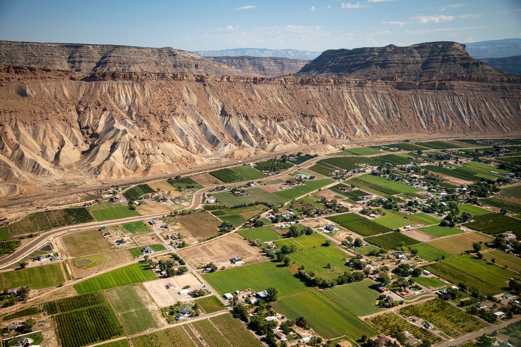 (Hugh Carey | The Colorado Sun via AP) Interstate 70 runs parallel to the Colorado River in parts of Palisade, Colo., near where the town famous for wineries and peaches, meets the high desert Book Cliffs, on Aug. 24, 2022.