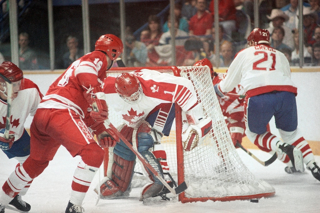 FILE - In this Feb. 24, 1988, file photo, a loose puck lies outside of the Canadian goal as Canadian goaltender Sean Burke and Soviet Union's Sergei Svetlov, left, go for it during an Olympic ice hockey medal round match at the Saddledome in Calgary. The 2018 Winter Games in Pyeongchang, South Korea will present a much different situation from any previous Olympic men’s hockey tournament in history. Before NHL players began participating in 1998, national teams were centralized and spent months together, much like women’s teams now, and the past five Olympics featured quick turnarounds on and off the 82-game NHL season. Because almost everyone in this tournament is playing professionally or in college, there isn’t much of an opportunity for training camps _ though Canada, Russia and other countries are making the most of any time they have to get together. (AP Photo/File)
