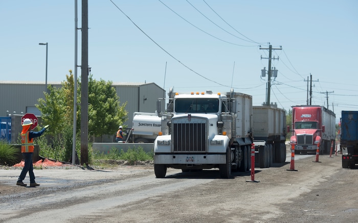(Rick Egan | The Salt Lake Tribune) Trucks make their way down Gladiola Street, as Salt Lake City Mayor Jackie Biskupski announces the start of the city’s 2018 road construction season at a new conference. A total of ten projects are scheduled for completion by the City’s Engineering Division through a combined investment of $5 million. Monday, June 11, 2018.