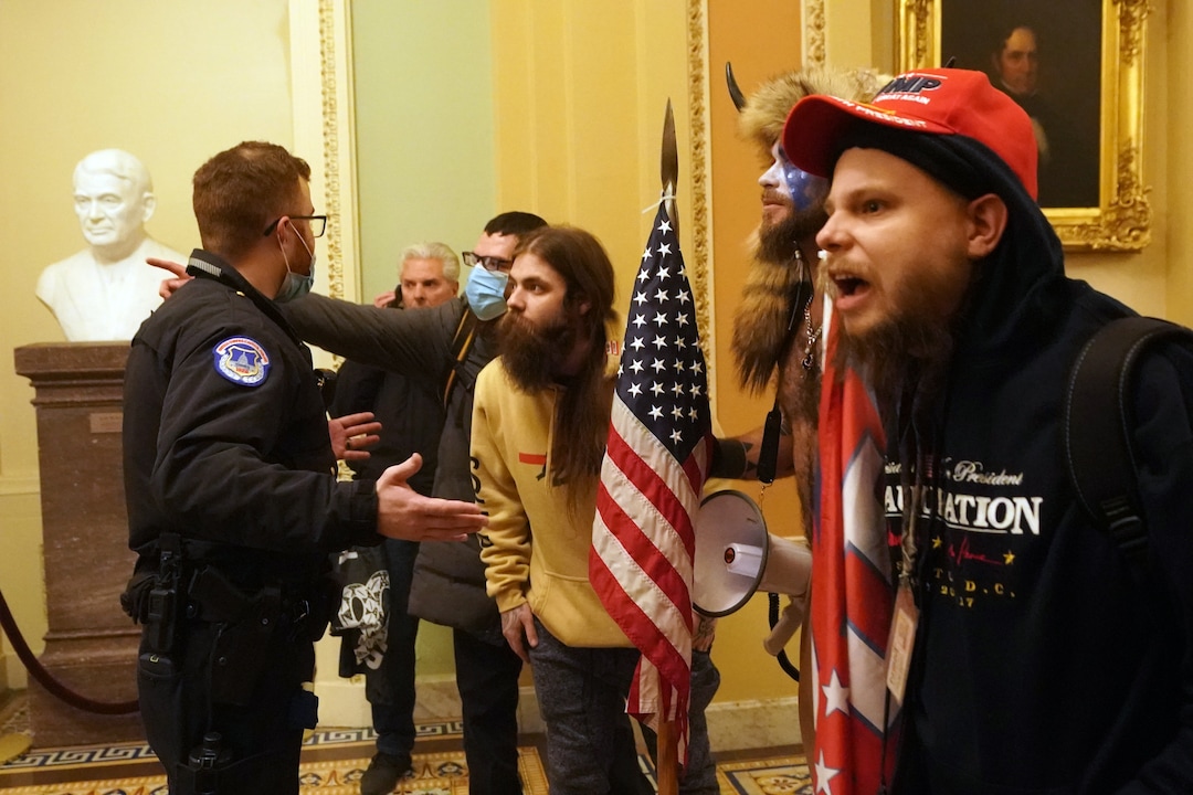 (Erin Schaff | The New York Times) A Capitol Hill police officer confronts people protesting the presidential election results inside the Capitol in Washington on Wednesday, Jan. 6, 2020. The Capitol building was placed on lockdown, with senators and members of the House locked inside their chambers, as Congress began debating President-elect Joe Biden’s victory. President Trump addressed supporters near the White House before protesters marched to Capitol Hill.