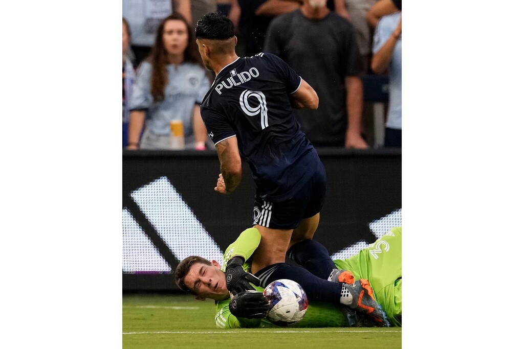 (Charlie Riedel | AP) Real Salt Lake goalkeeper Gavin Beavers, bottom, blocks a goal attempt by Sporting Kansas City forward Alán Pulido (9) during the first half of an MLS soccer match Wednesday, July 12, 2023, in Kansas City, Kan.