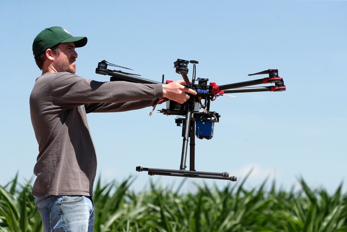 (David Zalubowski | AP Photo) In this Thursday, July 11, 2019, photograph, United States Department of Agriculture intern Alex Olsen prepares to place down a drone at a research farm northeast of Greeley, Colo. Researchers are using drones carrying imaging cameras over the fields in conjunction with stationary sensors connected to the internet to chart the growth of crops in an effort to integrate new technology into the age-old skill of farming.