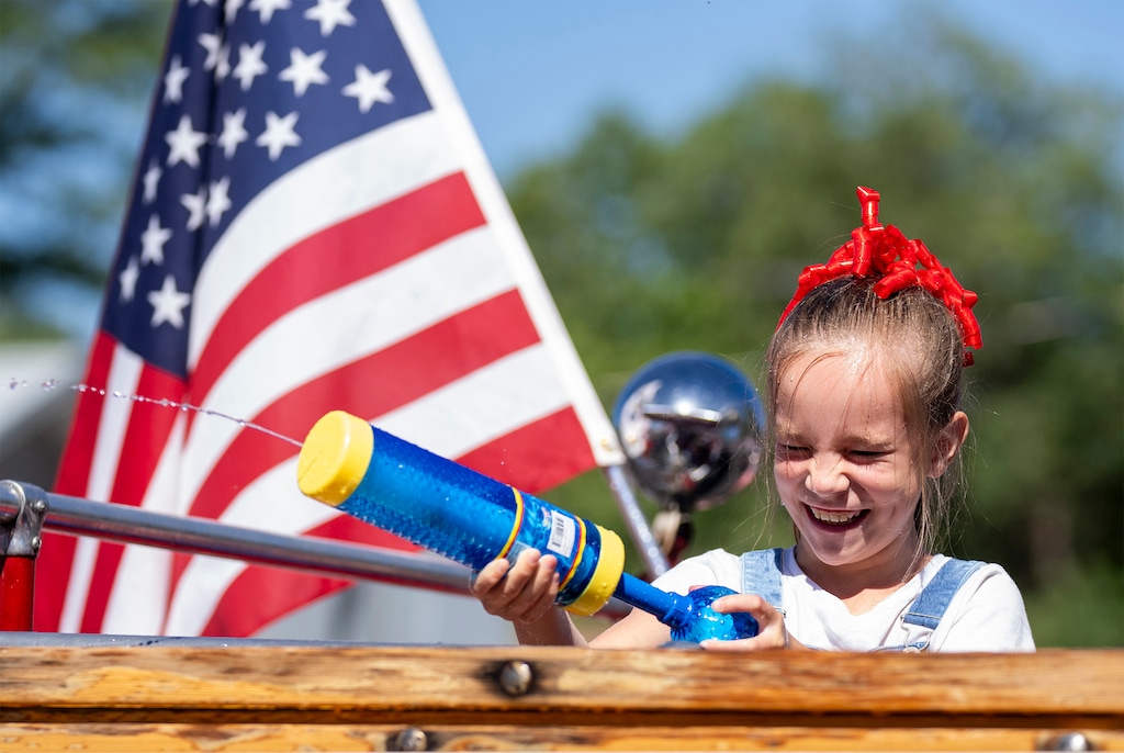 (Rick Egan | The Salt Lake Tribune)  Maggie Hopkin dodges a stream of water as she fires back into the crowd from a fire engine during an Independence Day parade in Morgan on Thursday, July 4, 2024.
