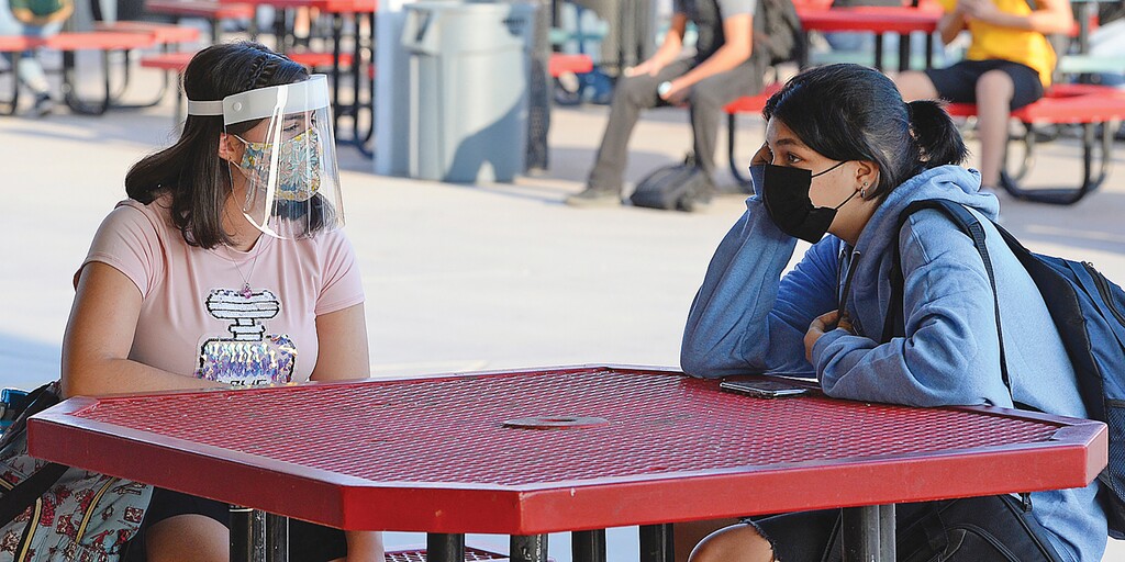 The second first day of school two students wearing protective face coverings have a conversation before the start of the first class during the coronavirus pandemic on the Gila Ridge High School campus, Thursday morning, Sept. 17, 2020, in Yuma, Ariz. (Randy Hoeft/The Yuma Sun via AP)
