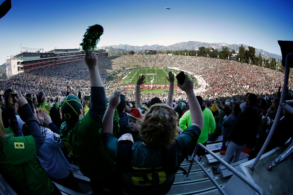 FILE - In this Jan. 1, 2015, file photo, Oregon fans cheer as their team takes to the field before the Rose Bowl NCAA college football playoff semifinal, in Pasadena, Calif. Group of Five teams will mostly play in third-tier bowl games in front of sparse crowds, earning payouts that mostly cover travel expenses. The Power Five teams get the glamor bowls with the multimillion-dollar payouts. (AP Photo/Richard Vogel, File)