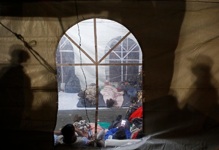 Exhausted family members of people believed to be buried inside a collapsed office building nap in a tent as rescuers continue trying to reach survivors, in the Roma Norte neighborhood of Mexico City, shortly after midnight Saturday Sept. 23, 2017.(AP Photo/Rebecca Blackwell)