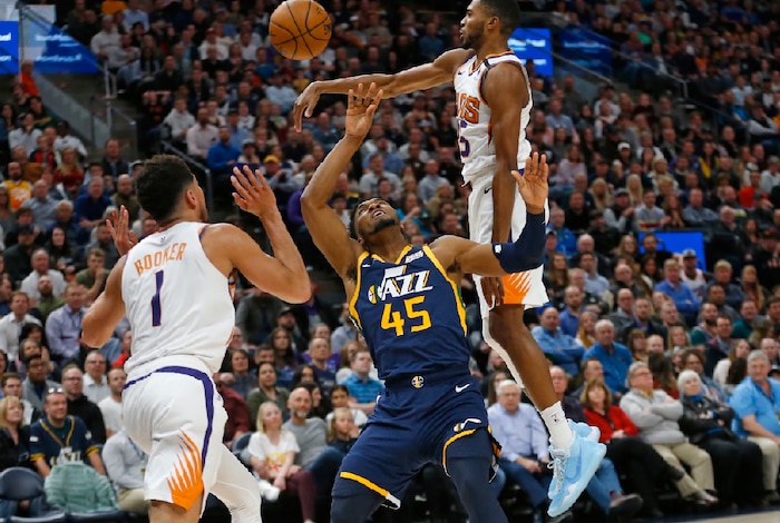 Utah Jazz guard Donovan Mitchell (45) loses the ball after being fouled by Phoenix Suns guard Devin Booker (1) while driving to the basket in the first half during an NBA basketball game Monday, Feb. 24, 2020, in Salt Lake City. (AP Photo/Rick Bowmer)