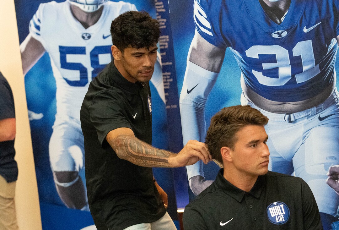 (Francisco Kjolseth | The Salt Lake Tribune) Wide receiver Samson Nacua, left, tries to clip a clothes pin on tight end Dallin Holker as he’s interviewed by print media as BYU football coaches, players and staff participate in BYU football media day in the BYU Broadcasting Building in Provo on Thursday, June 17, 2021.