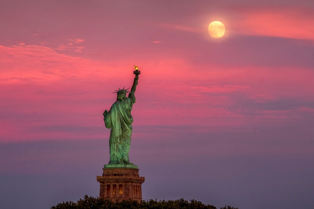 The full moon rises behind the Statue of Liberty at sunset in New York City, Monday, July 15, 2019, on the night before the 50th anniversary of the Apollo 11 moon launch. (AP Photo/J. David Ake)