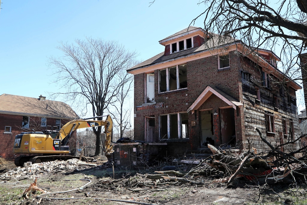 In this Thursday, April 19, 2018, photo, an excavator sits at the site of a house demolition in Detroit. The city has torn down more than 14,000 structures over the past four years. Concern over contaminated dust from lead-based paint in older houses has resulted in the city pushing back some demolitions in parts of the city where elevated blood lead levels have been found in children. (AP Photo/Carlos Osorio)