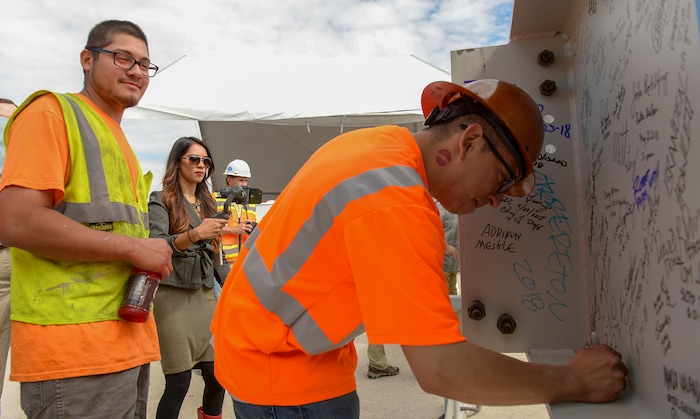 (Leah Hogsten  |  The Salt Lake Tribune) l-r Giovanni Zavala and Adolfo Velazquez with Pete King Framing sign their name to the beam during Wednesday's "topping out" ceremony to raise the last steel beams to a high point on the new terminal building, Wednesday, May 23, 2018. The new $485 million terminal building will cover 866,087 square feet and used 11,000 tons of structural steel and 22 miles of steel piles.